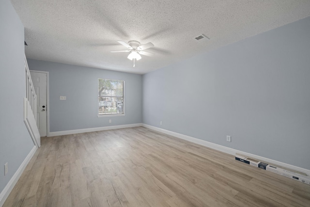 unfurnished room with a textured ceiling, light wood-type flooring, and ceiling fan