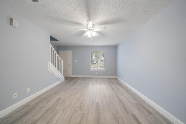 spare room with ceiling fan, light wood-type flooring, and a textured ceiling