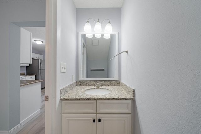 bathroom with wood-type flooring, vanity, and a textured ceiling