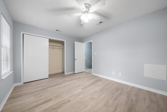 unfurnished bedroom with light hardwood / wood-style flooring, a closet, a textured ceiling, and ceiling fan