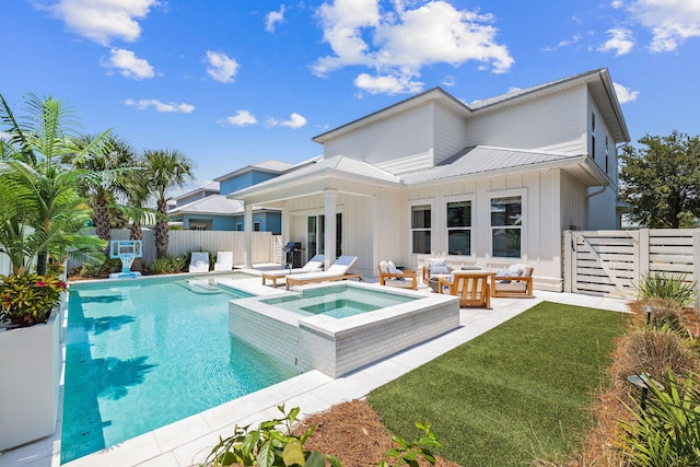 back of property with a patio, a lawn, and a swimming pool with hot tub