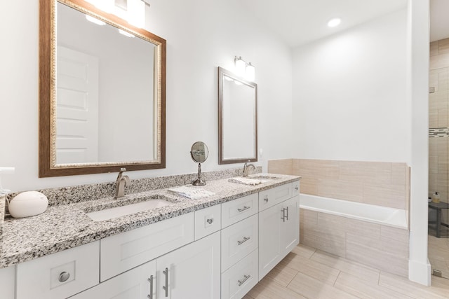 bathroom featuring a relaxing tiled tub, tile patterned floors, and dual bowl vanity