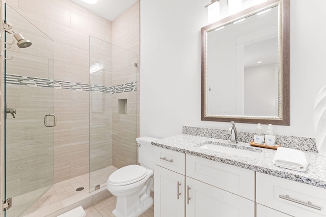 bathroom featuring vanity, a shower with door, and toilet