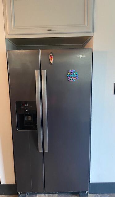 interior details with stainless steel refrigerator with ice dispenser and white cabinetry