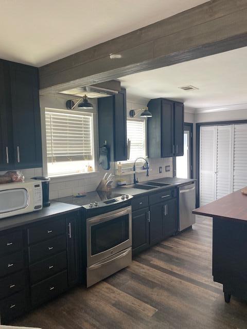 kitchen featuring blue cabinetry, dark hardwood / wood-style floors, stainless steel appliances, and sink