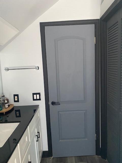 bathroom with vaulted ceiling, vanity, and hardwood / wood-style flooring