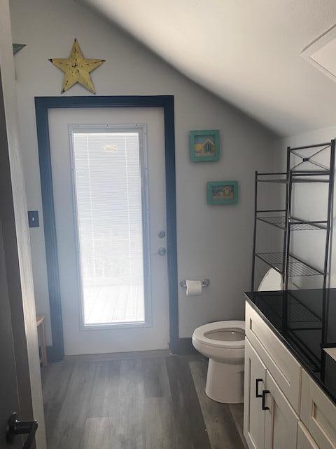 bathroom featuring vanity, toilet, hardwood / wood-style floors, and vaulted ceiling