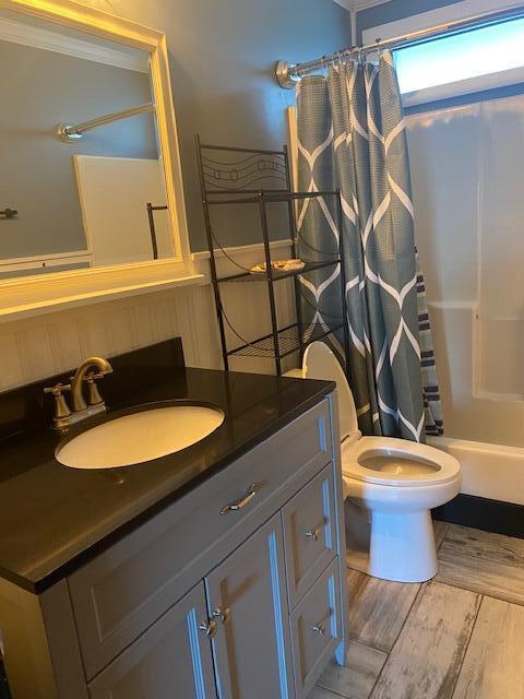 full bathroom with shower / bath combo with shower curtain, wood-type flooring, vanity, and toilet