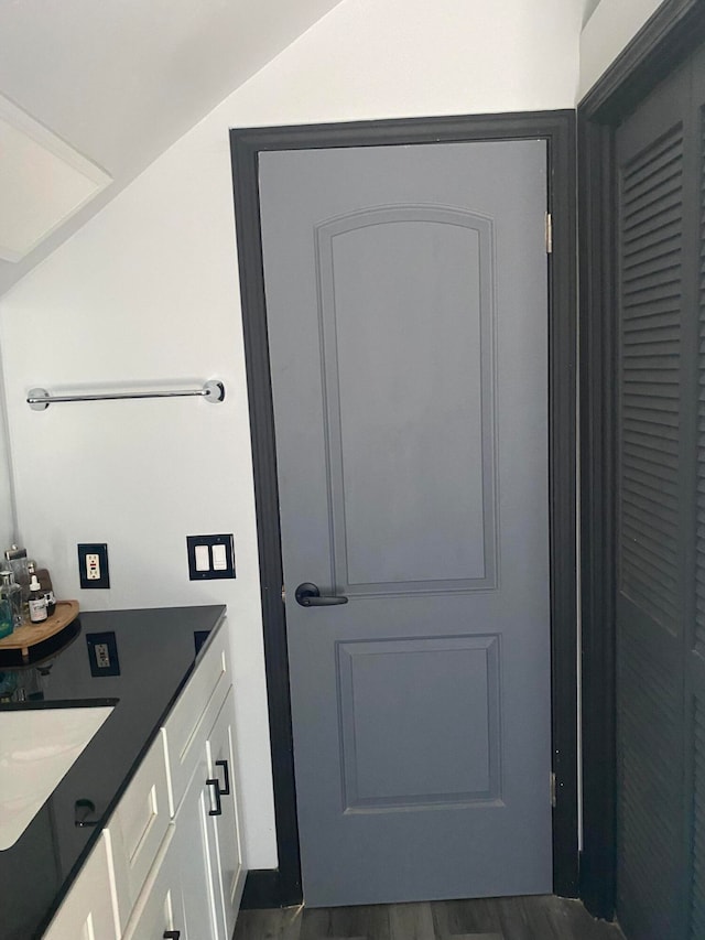 bathroom with lofted ceiling, vanity, and wood-type flooring