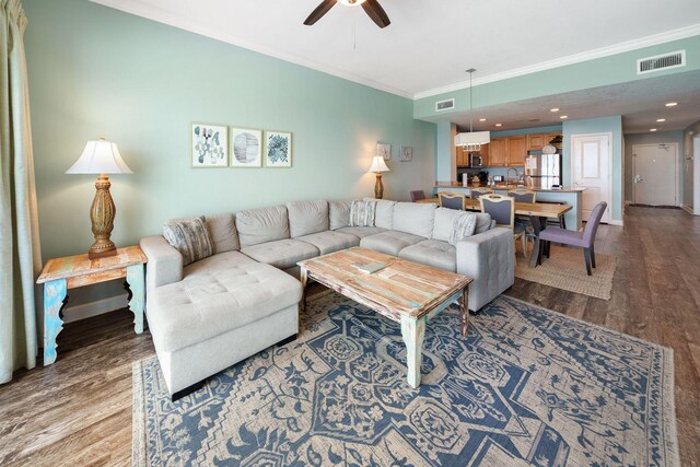 living room featuring visible vents, baseboards, ornamental molding, wood finished floors, and a ceiling fan