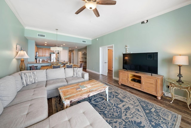 living room featuring dark wood-style flooring, visible vents, ceiling fan, and ornamental molding