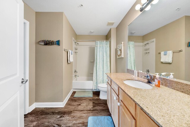 bathroom featuring baseboards, shower / bath combo with shower curtain, toilet, wood finished floors, and vanity