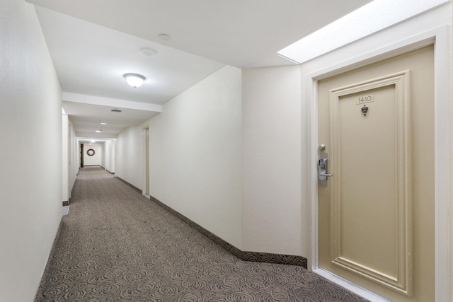 hallway featuring a skylight and baseboards