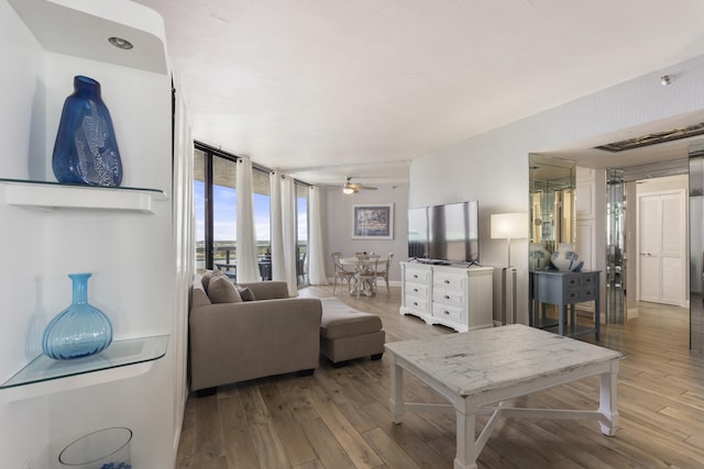 living area with a ceiling fan, baseboards, floor to ceiling windows, and wood finished floors