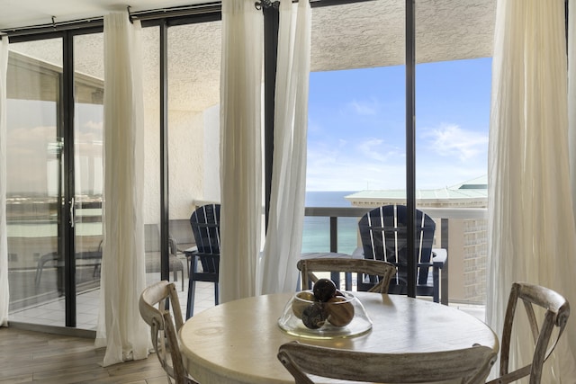 dining space with a water view, light wood-style floors, and expansive windows