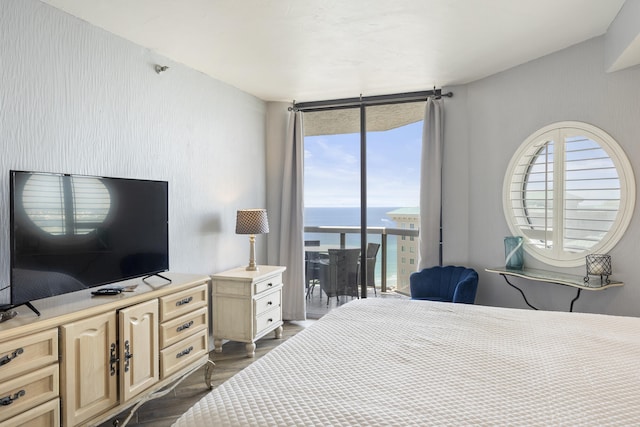 bedroom with a water view, access to exterior, and dark wood-type flooring