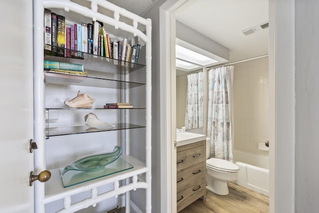 bathroom featuring toilet, shower / bath combo, visible vents, and wood finished floors