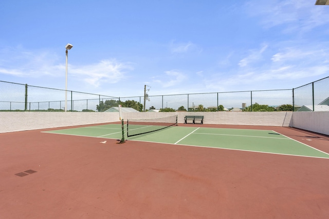 view of tennis court featuring community basketball court and fence