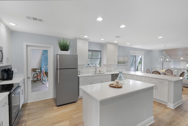 kitchen with white cabinets, a center island, stainless steel appliances, light hardwood / wood-style floors, and sink