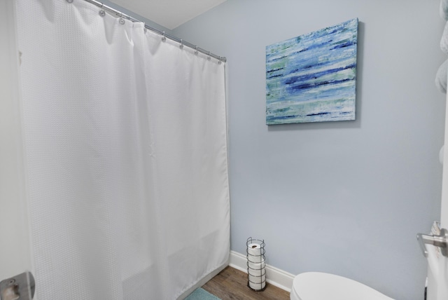 bathroom featuring wood-type flooring, toilet, and a shower with shower curtain