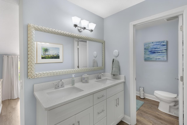 bathroom featuring wood-type flooring, toilet, and vanity