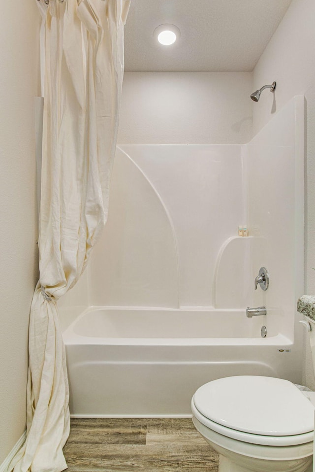 bathroom featuring toilet, shower / bathtub combination with curtain, a textured ceiling, and hardwood / wood-style flooring