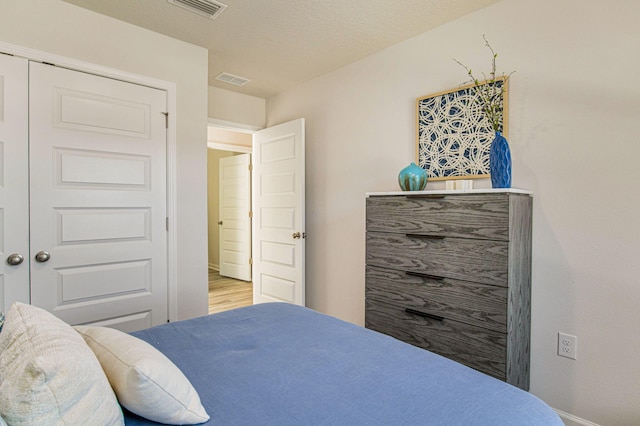 bedroom with a textured ceiling, light hardwood / wood-style flooring, and a closet