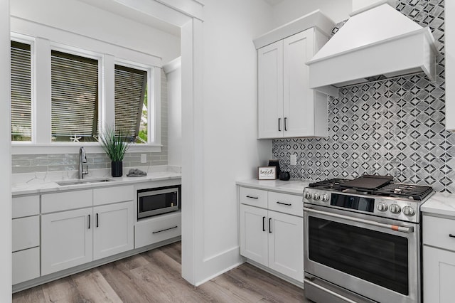 kitchen featuring sink, white cabinets, stainless steel appliances, and light hardwood / wood-style floors