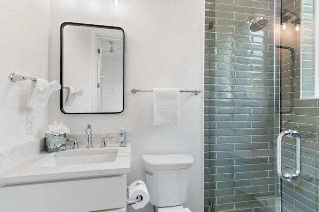 bathroom with toilet, vanity, and a shower with shower door