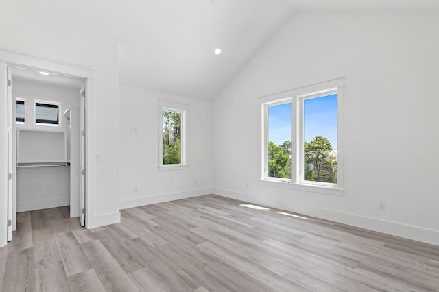 unfurnished bedroom featuring high vaulted ceiling, light wood-type flooring, and a closet