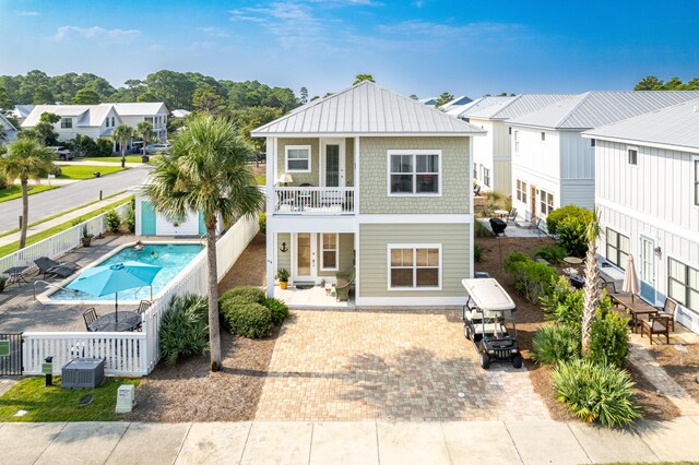 back of house with central AC, a fenced in pool, a patio area, and a balcony