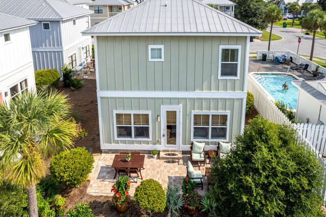 rear view of property with a fenced in pool and a patio area