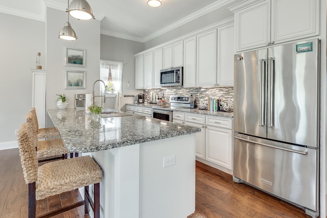 kitchen featuring appliances with stainless steel finishes, a breakfast bar area, white cabinets, hardwood / wood-style floors, and sink