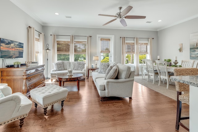 living room featuring hardwood / wood-style floors, ornamental molding, and ceiling fan