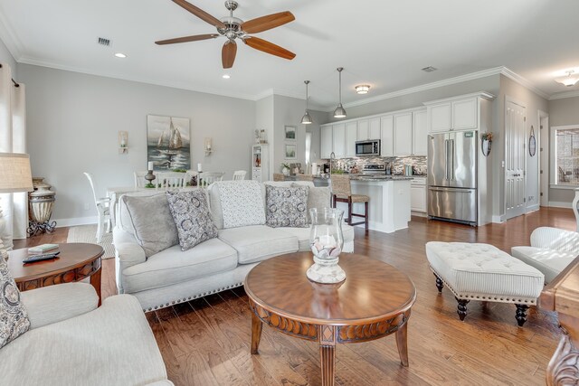 living room featuring ceiling fan, wood-type flooring, and ornamental molding