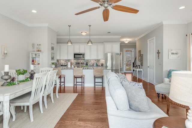 living room featuring light hardwood / wood-style flooring, crown molding, and ceiling fan