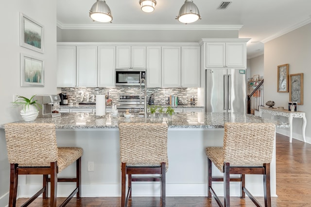 kitchen featuring white cabinets, backsplash, stainless steel appliances, and hardwood / wood-style floors