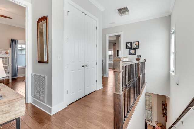 corridor featuring hardwood / wood-style flooring, plenty of natural light, and ornamental molding