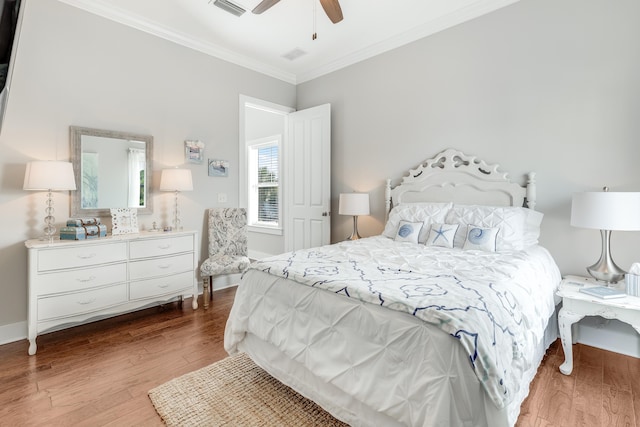 bedroom featuring hardwood / wood-style floors, ornamental molding, and ceiling fan