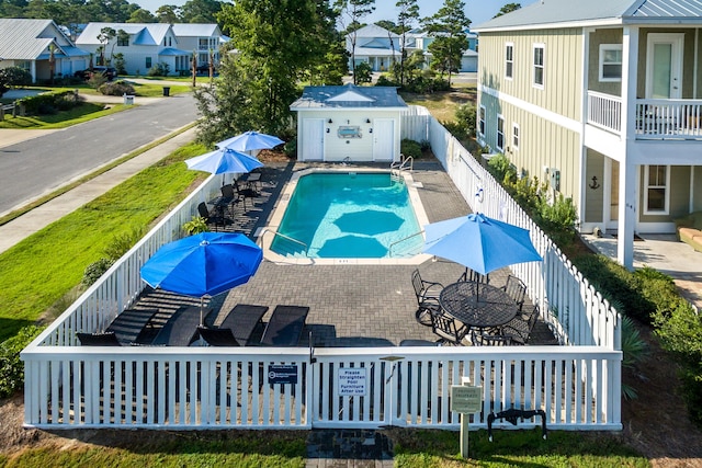 view of swimming pool featuring a patio area and a storage shed