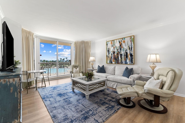 living room featuring light wood-type flooring, ornamental molding, and expansive windows