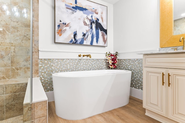 bathroom featuring tile walls, a bathing tub, hardwood / wood-style flooring, and vanity