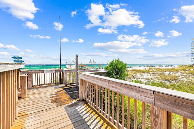 wooden terrace featuring a beach view and a water view