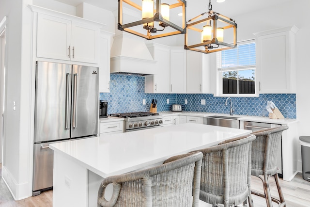 kitchen featuring high end appliances, white cabinets, a kitchen breakfast bar, and pendant lighting