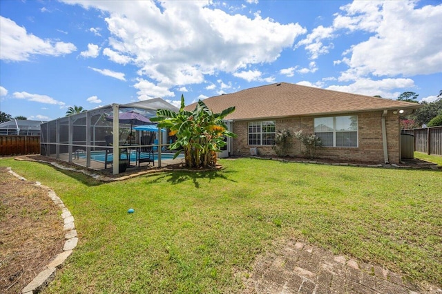 rear view of property featuring glass enclosure, a fenced in pool, and a yard