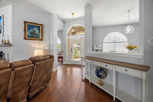 entryway with dark wood-type flooring and an inviting chandelier