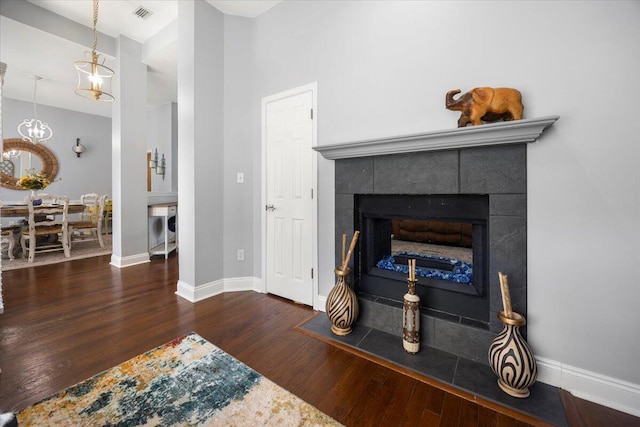 living room featuring a tiled fireplace, an inviting chandelier, and hardwood / wood-style floors