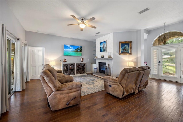 living room featuring a large fireplace, dark wood-type flooring, and ceiling fan