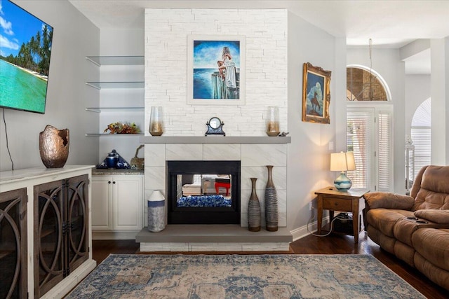 living room featuring built in features, a multi sided fireplace, and dark hardwood / wood-style floors