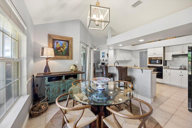 tiled dining area with an inviting chandelier and lofted ceiling